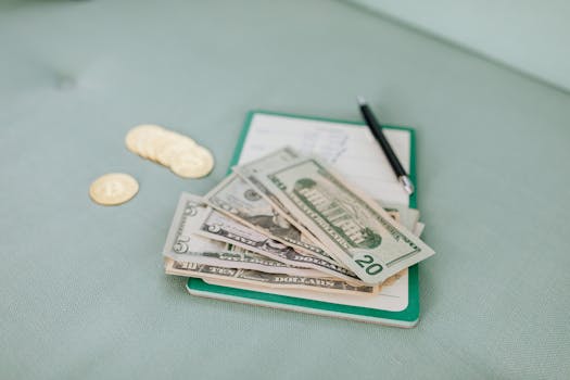 Close-up of American dollar bills and coins on a journal with a pen, representing budget planning.